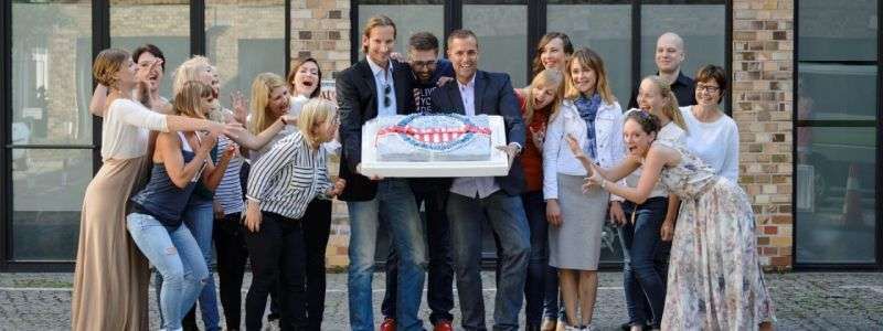 Il team di The American Dream si è riunito intorno a una grande torta.
